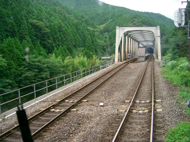 発車してから駅を見た、上下線の線路の間にホームへの階段の屋根が見える、その屋根の向こにホーム